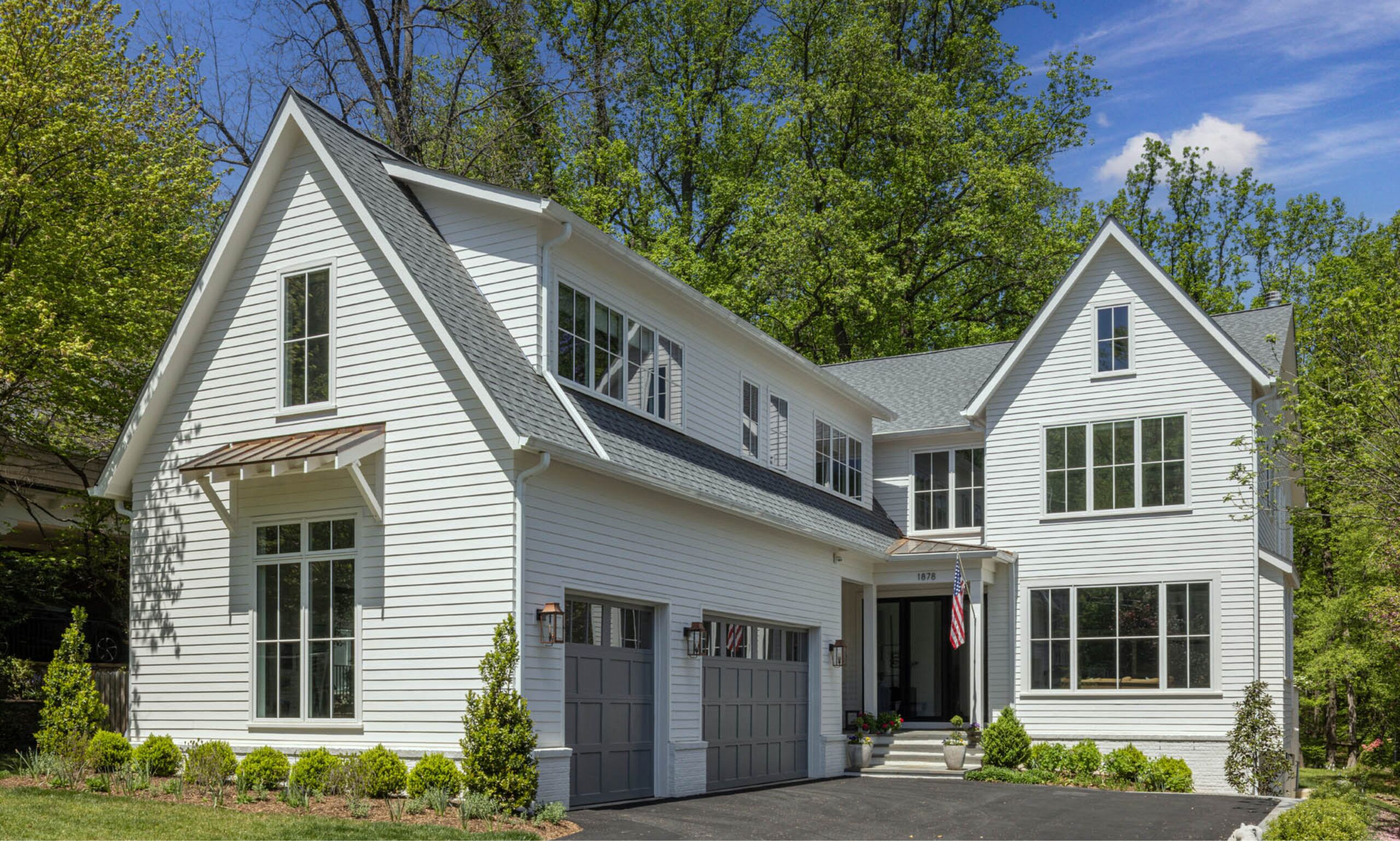 A street-level view of a white house with a two-car garage