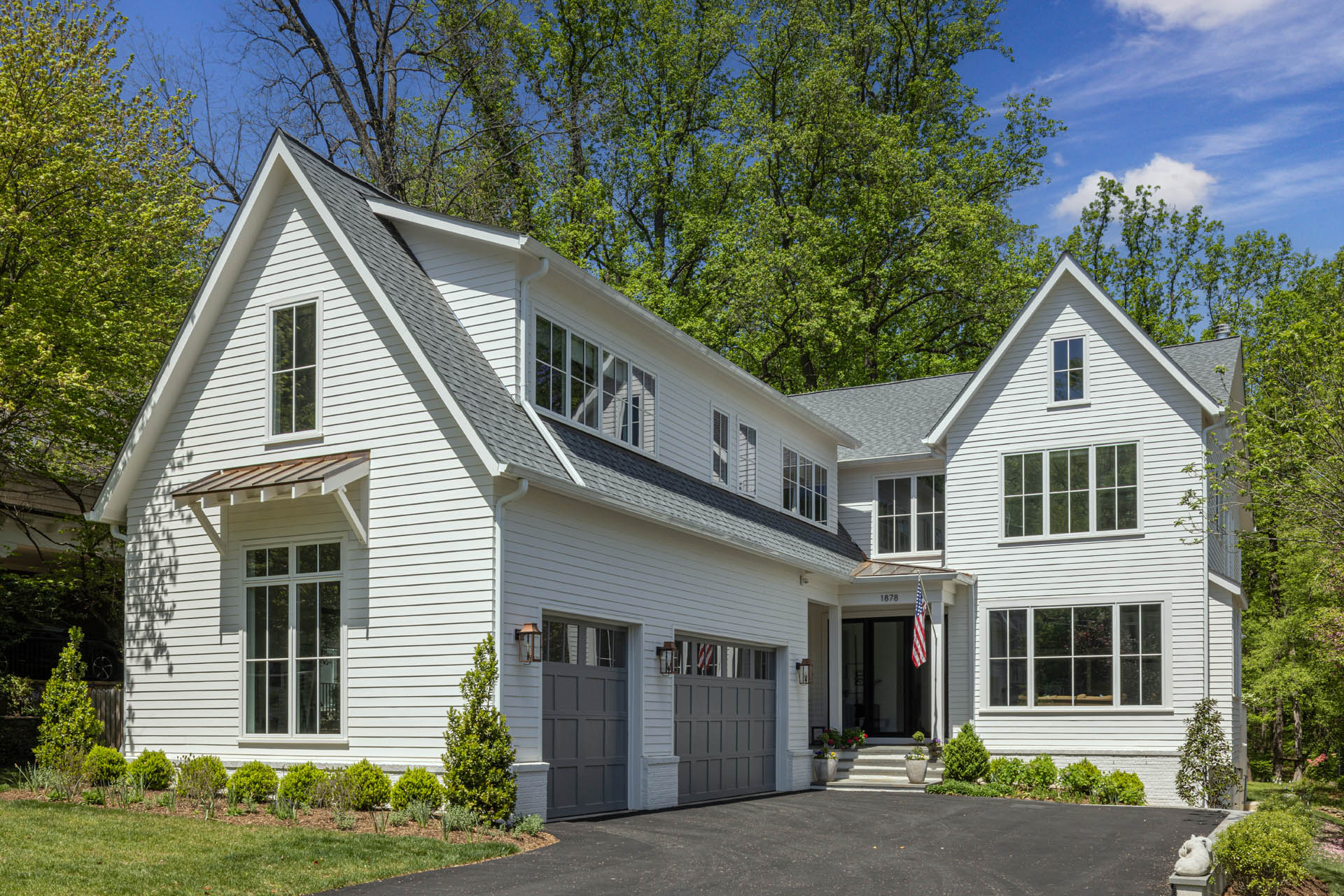 A street-level view of a white house with a two-car garage