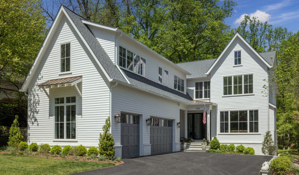A street-level view of a white house with a two-car garage