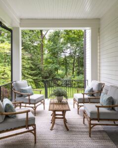 The front porch of a house with four wooden chairs seated around a wooden coffee table