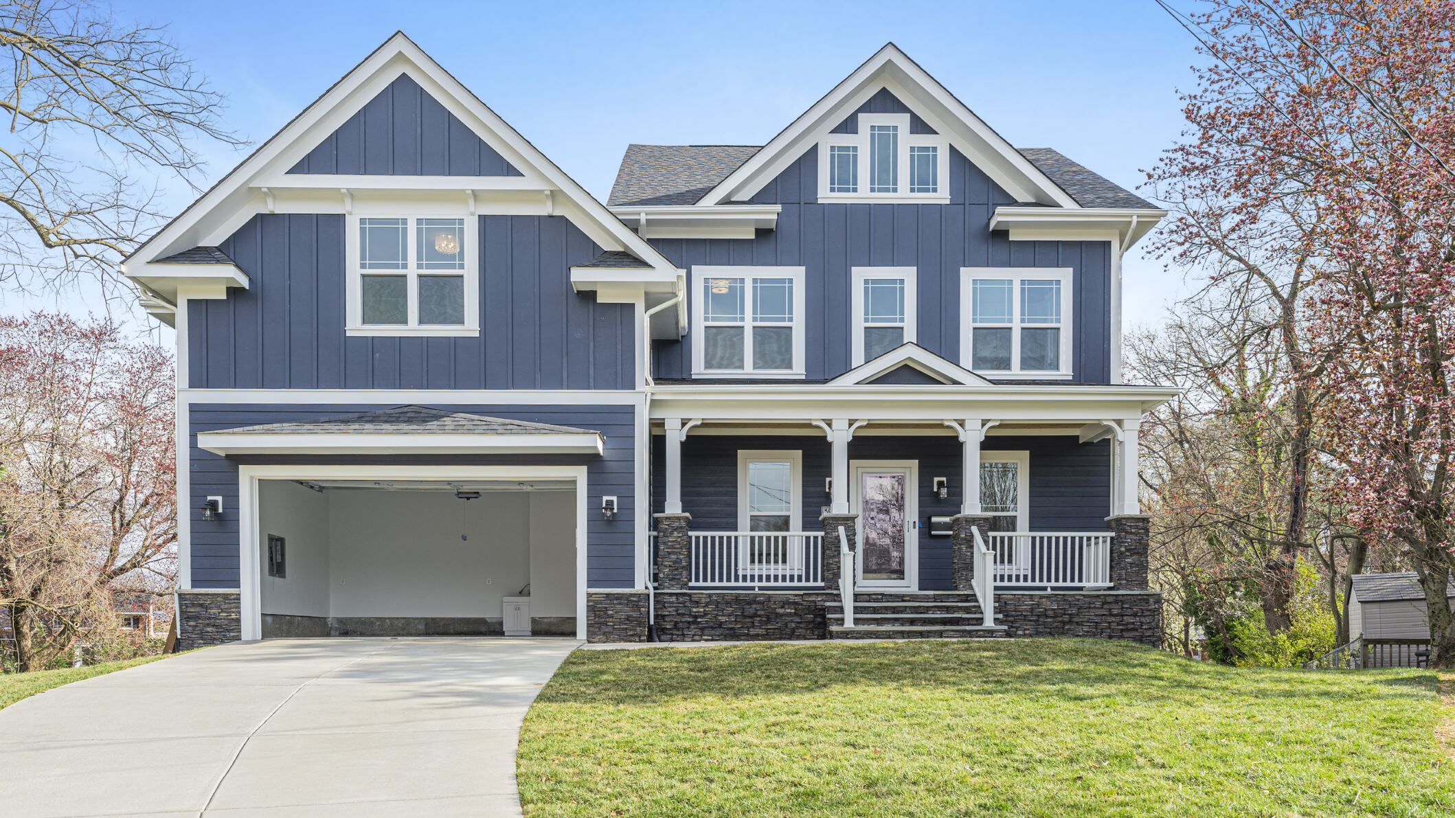 A blue house with a driveway leading to an open car garage