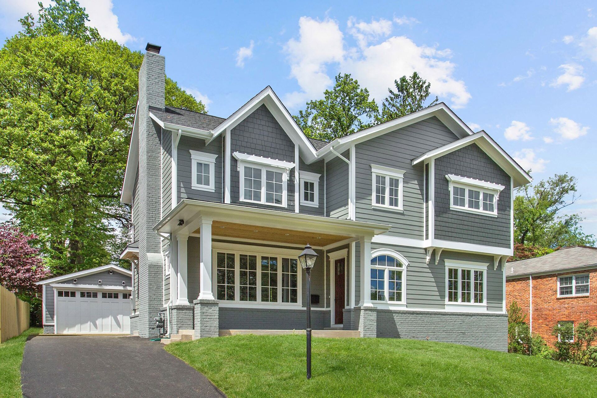 A gray house with a sloped driveway leading up to a detached garage