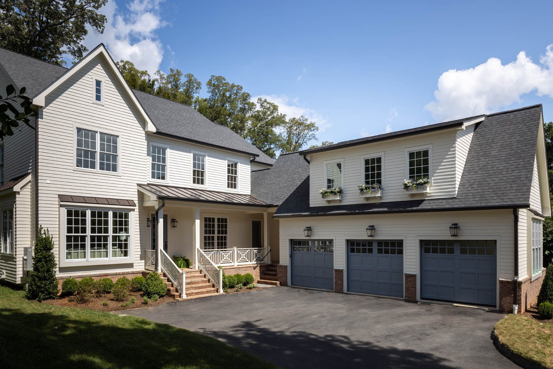 A from-afar view of a white house with a partially detatched three-door car garage