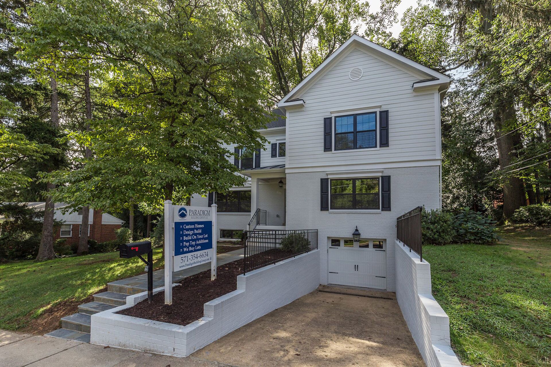 A white house with a downward-sloping path leading to the attached car garage