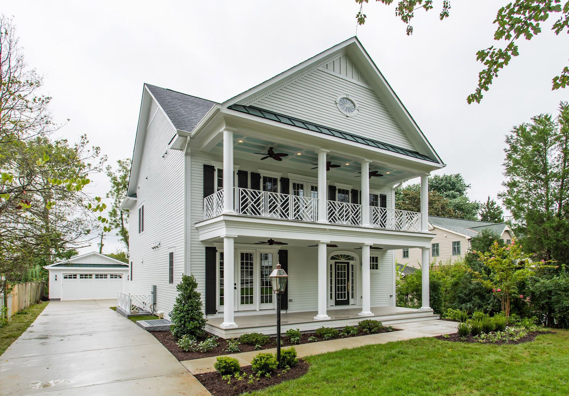 A white house on a rainy day with a driveway leading to a detatched car garage