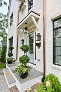 A sideways view of the entrance of a white house with golden pipes