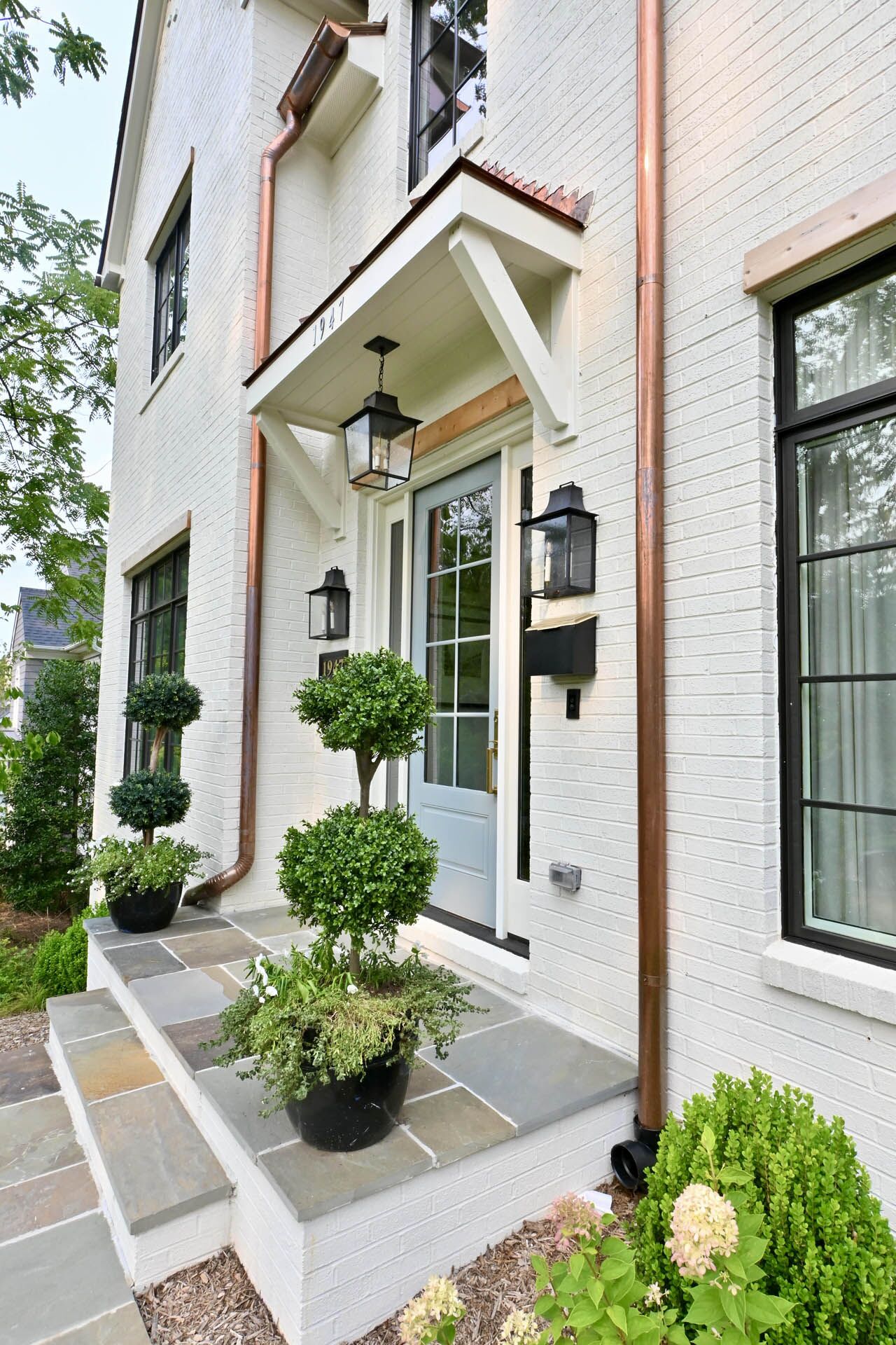 A sideways view of the entrance of a white house with golden pipes
