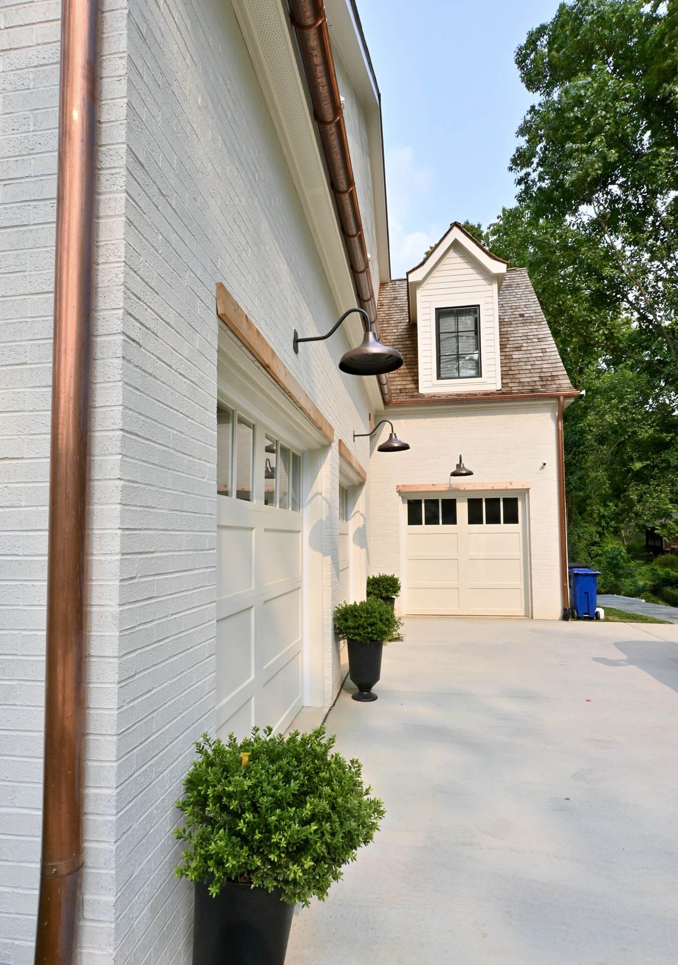 A garage-level view of a white house with golden pipes