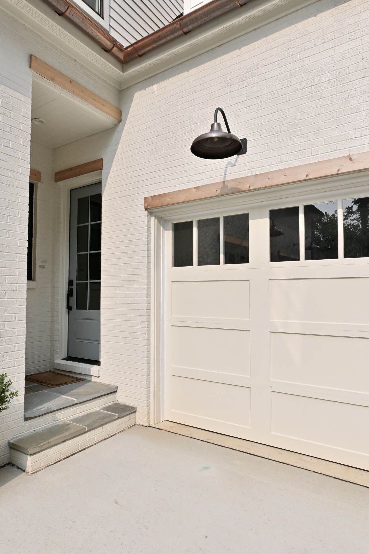 A white garage in the foreground with the entrance to the house in the back