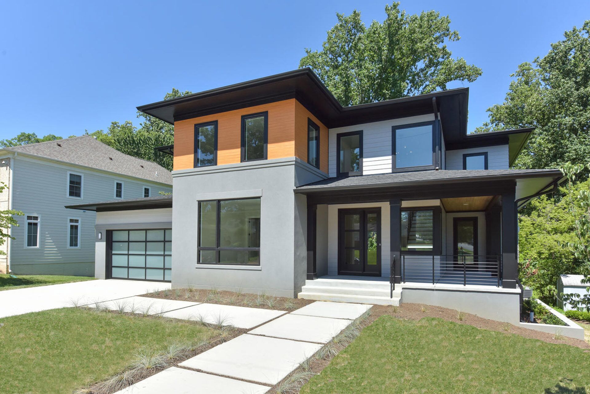 A multi-colored modern house with a pavers sidewalk leading up to the front door