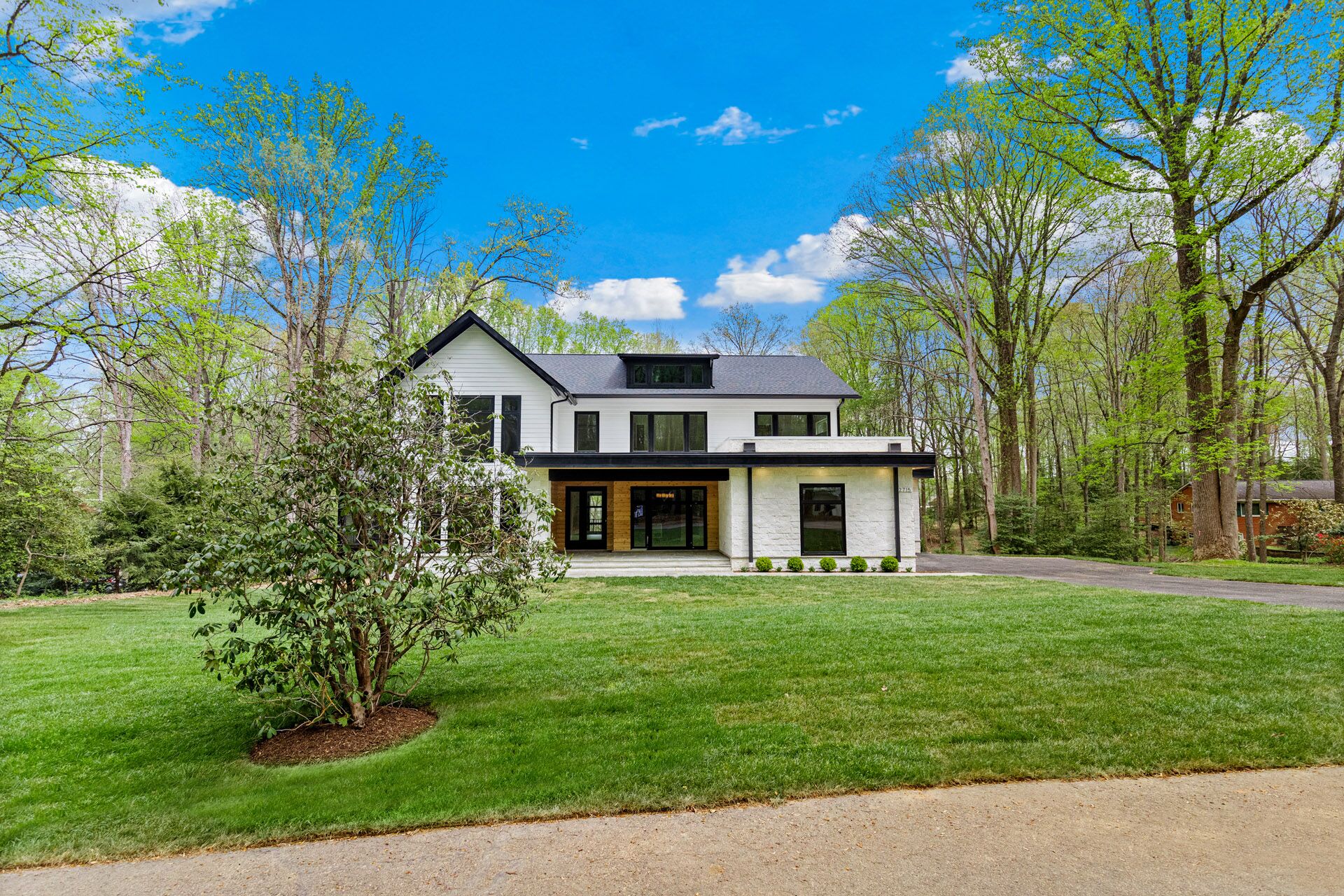 A white house with several leafy trees growing on either side