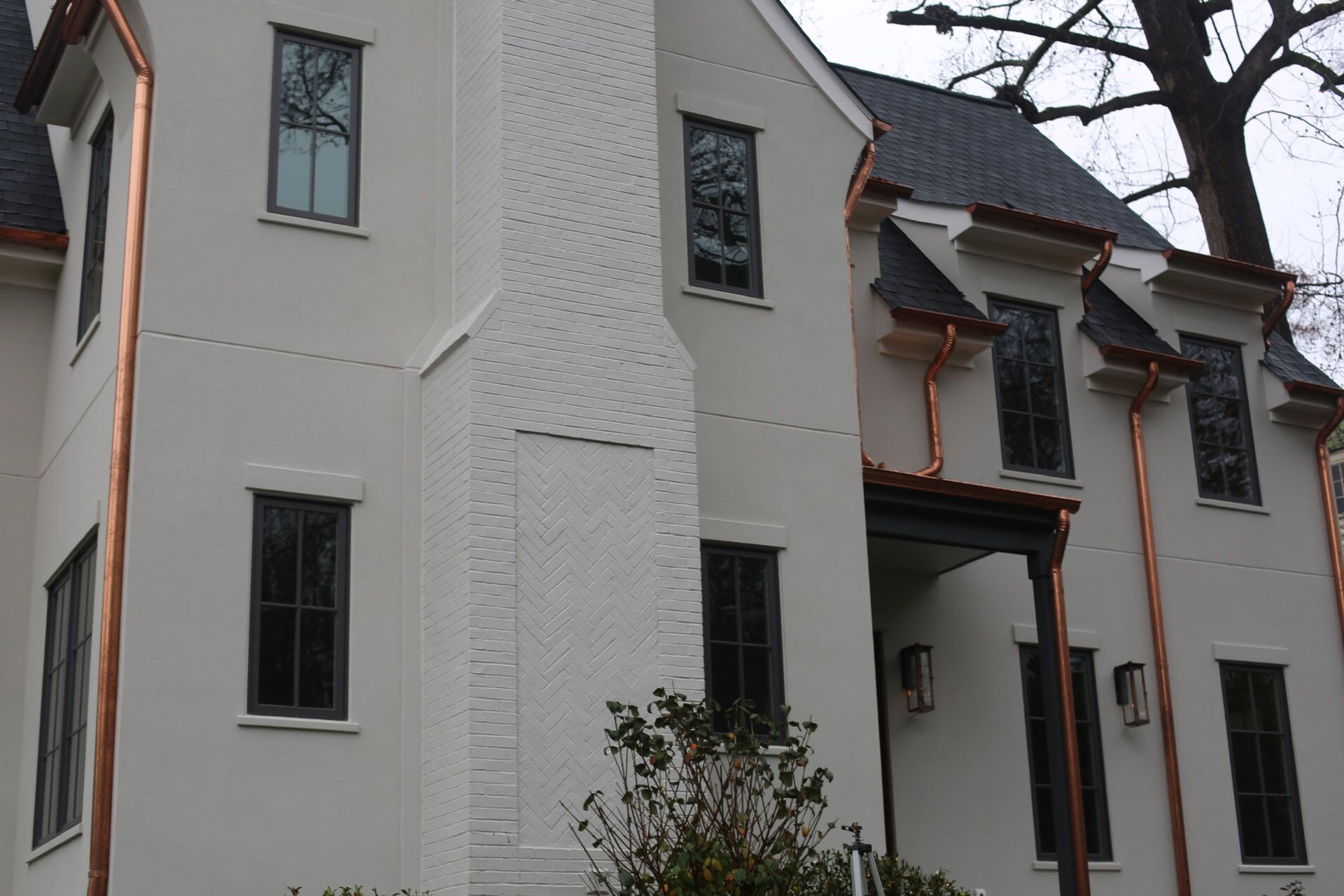 A white house with gold pipes and a black slatted roof