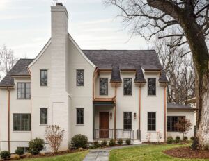 A white house with gold pipes and a black slatted roof