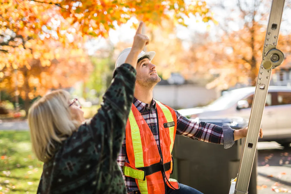 A woman showing roof damage to an insurance adjuster.
