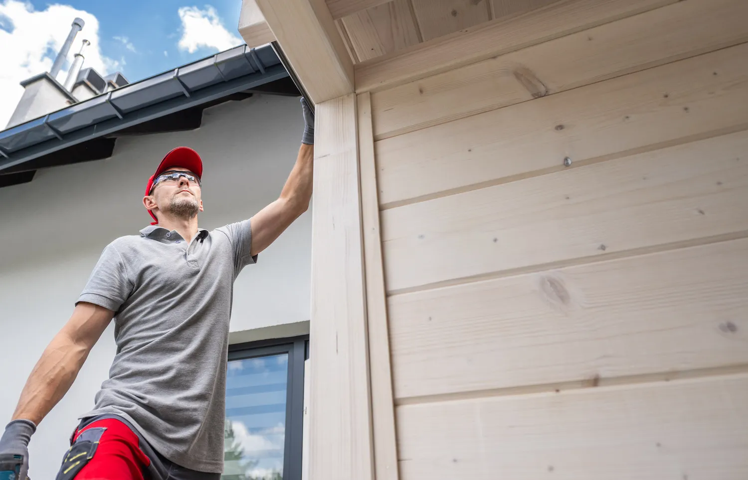 A man inspecting siding on a house.